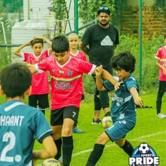 A young player skillfully shields the ball from a defender, showcasing the close-control dribbling techniques we emphasize in our coaching.