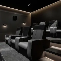 A closer look at the premium recliners in the 'Shadow Luxe' design. Notice the ergonomic support, built-in cup holders, and sleek finish that combines comfort with a modern aesthetic. The subtle wall sconces provide just enough ambient light without distracting from the screen.