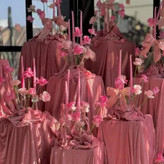 A close-up of the dramatic, multi-level centerpiece, featuring cascading pink velvet, dozens of pink taper candles, and delicate flowers.