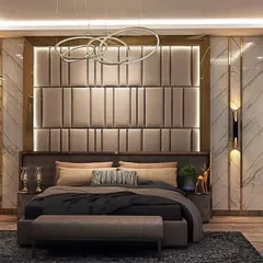 This bedroom design features a striking padded headboard with vertical grooves and a gold metal frame. The combination of marble walls, warm lighting, and plush textiles creates an atmosphere of sophisticated comfort.