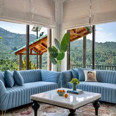 The living area is designed for comfort, with custom fluted sofas in a calming blue, set against the backdrop of the stunning mountain scenery.