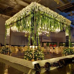 For a more contemporary feel, I created this elegant wedding mandap featuring a cascade of white flowers and fresh greenery. The mirrored pillars and soft lighting give it a sophisticated and modern look, perfect for an indoor convention hall setting.