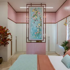 This Indian contemporary bedroom is designed for a daughter, blending playful pastels with sophisticated elements. The room features a pink upholstered bed, floral wallpaper, and a unique partition that doubles as a dressing table, creating a space that is both beautiful and functional.