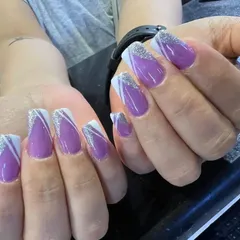 A glamorous take on the French manicure. These coffin-shaped nail extensions feature a rich purple base with elegant white lines and a sparkling silver glitter finish on the tips.