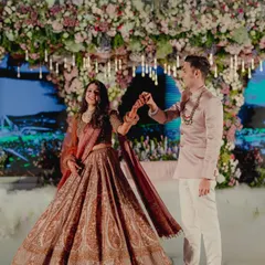 A dance between the couple at their reception. The bride's paisley-printed lehenga in muted tones and the groom's sleek blush bandhgala jacket create an elegant and romantic look, perfect for an evening celebration.