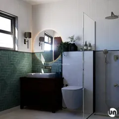 This bathroom design features aqua subway tiles laid in a herringbone pattern, creating a beautiful feature wall. Paired with a backlit mirror and simple, textured white tiles, it creates a standard of elegance that is both modern and timeless.