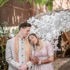 A sweet and peaceful moment, with the bride resting her head on the groom's shoulder under a canopy of white flowers.