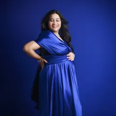 A quiet moment of joy. This portrait focuses on the mother-to-be's happy expression, with the rich blue gown providing a beautiful, vibrant frame.