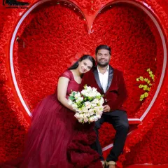 A romantic pre-wedding portrait using my heart-themed studio backdrop. I provide coordinated outfits, like this couple's maroon gown and velvet blazer, to create a perfectly styled shot.