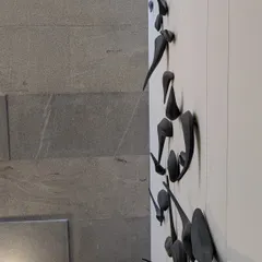 A side view of the bird sculpture, showing the three-dimensional quality and the way the pieces cast soft shadows.