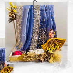 This Teej hamper showcases a stunning blue organza saree with intricate gold embroidery. We complemented it with yellow flowers, dried wheat stalks, and a custom-draped saree doll to create a beautiful and cohesive gift.