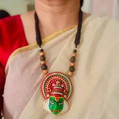 This Kathakali-inspired terracotta pendant features the iconic green face paint of the heroic protagonist. It's a striking piece of wearable art, perfect for celebrating cultural festivals like Onam.