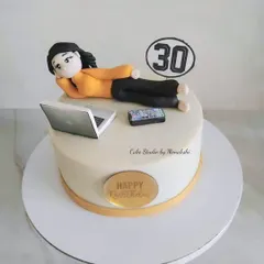 A special 30th birthday cake for a workaholic. This design features a handcrafted figurine relaxing with her laptop and phone, a perfect way to add a personal and humorous touch.