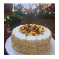 My fresh fruit cake, generously coated with sliced almonds for a delightful crunch. It's topped with a medley of seasonal fruits like kiwi, grapes, and pineapple.