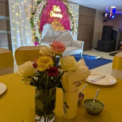 A close-up of a guest table centerpiece with fresh roses, with the beautifully decorated Roka stage visible in the background.