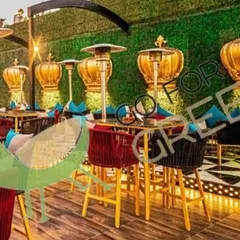A vibrant shot of the rooftop at Lord of The Drinks in Agra, furnished by us. This image shows our colorful red and black rope bar chairs, dining sets, and the striking green wall we installed. The unique crown-shaped decor highlights the premium, customized look we can help create.