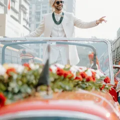 The groom arriving in style in a vintage red car. We arrange for unique transportation to make the baraat procession truly memorable.
