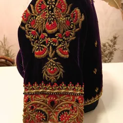 A close-up of the sleeve of the purple velvet blouse, highlighting the rich zardozi and red threadwork. This level of detail shows the quality and intricacy of the designer blouses we help you rent out.