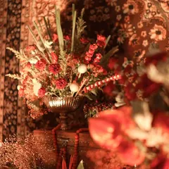 A close-up of a Souk Bazaar theme, capturing the rich, warm ambiance with red floral arrangements, antique tapestries, and soft, glowing light.