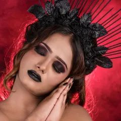 A close-up of the gothic makeup with eyes closed to showcase the deep, blended eyeshadow. The look is paired with black nails and a dramatic headpiece against a red, smoky background.