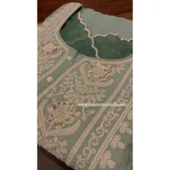 A close-up of the exquisite embroidery on a sage green kurta. The intricate threadwork is complemented by carefully placed sequins, adding a subtle shimmer to the piece.