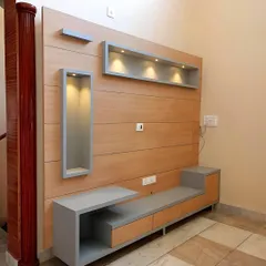 For this project, we created a minimalist TV unit using a light wood laminate and contrasting grey accents. The design features an asymmetrical layout with both open and closed storage, including illuminated display niches for showcasing decor.