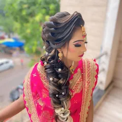 A glamorous and intricate braided hairstyle perfect for a sangeet or reception. This look features a combination of twists and a long, flowing braid decorated with pearls, with soft highlights adding dimension.