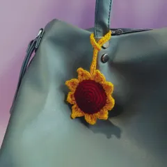 A bright and cheerful sunflower bag charm attached to a handbag. This little accessory is a simple way to add a pop of color and personality to your everyday look.