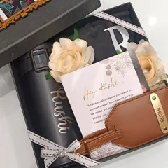 A farewell gift box for a colleague named Rushi. This hamper includes a custom coffee sipper, a personalized luggage tag, a t-shirt, and a heartfelt 'We will miss you' card from the team.