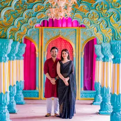 The vibrant colors of our Rajasthani palace set, with its turquoise pillars and pink curtains, create a stunning and lively background for any couple's portrait.