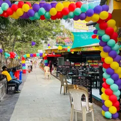 A long walkway at an outdoor venue decorated with a vibrant, multi-colored balloon arch to create a festive pathway.