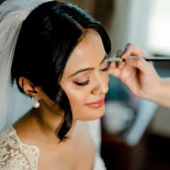 A close-up of the makeup process for a Catholic bride. I'm applying a soft, shimmery eyeshadow to create a romantic and eye-catching look that's perfect for a white wedding.