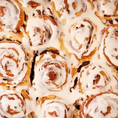 A top-down shot of delicious cinnamon rolls for the dessert shop, It's Minidonuts. This perspective highlights the beautiful swirl pattern and creamy icing, making it a perfect shot for social media feeds.