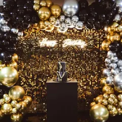 You can never go wrong with a bit of sparkle. This glamorous birthday backdrop features a shimmering gold sequin wall, a custom 'Happy Birthday' neon sign, and a dramatic balloon arch in black, gold, and silver. It’s designed to make a statement.
