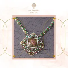 A unique and artistic necklace featuring intricate filigree work and a central motif with rubies and emeralds. This piece is a modern tribute to traditional Indian craftsmanship.