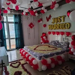 This is a very detailed first night decoration I did in a client's home. The setup includes 'Just Married' balloons, rose petal hearts on the bed and floor, and a border of red and white balloons around the bed.