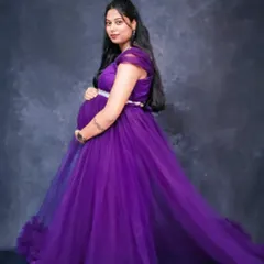 A three-quarter portrait showing a mom-to-be cradling her bump. The dark, textured backdrop makes the purple of the gown pop, creating a rich and moody image.