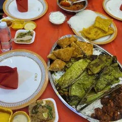 A traditional table setting with a variety of main course dishes, including fish steamed in banana leaves, rich curries, and fresh breads.