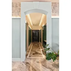 A full view of the arched entrance into the green foyer. The combination of the marble arch, fluted side panels, and architectural wallpaper creates layers of texture and grandeur.