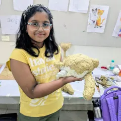 A student proudly holds up her papermache teddy bear before the painting process begins. Building the form is the first and most important step in 3D sculpture.