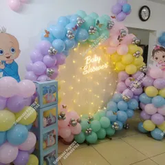 A beautiful pastel rainbow balloon ring for a baby shower, with a neon sign and "BABY" blocks.