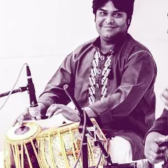 A pleasant portrait of me with my tabla, taken during a concert. I am seated on the stage, looking towards the audience before or after a performance.