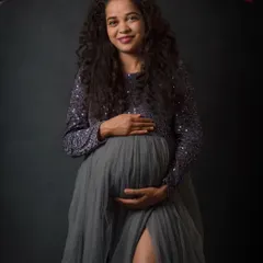 A gentle, classic pose for a maternity portrait. The focus here is on the mother's happy expression and the loving way she holds her baby bump, creating a warm and timeless memory.