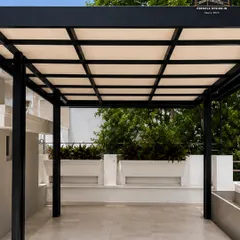 A clean and contemporary design for a spacious terrace. This black powder-coated steel pergola with a light-diffusing roof provides ample shade while maintaining a bright and airy feel, making the space perfect for daytime use.