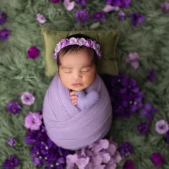 A sweet newborn girl swaddled snugly in purple, surrounded by delicate flowers. We love incorporating color to create unique and beautiful newborn art.
