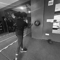 A black and white shot of a client performing a medicine ball throw.
