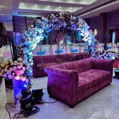 A breathtaking floral archway designed as a seating area for guests. We used a mix of blue, white, and pink flowers with hanging greenery to create a lush, garden-like atmosphere inside the venue, complemented by dramatic uplighting.
