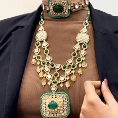 A masterclass in modern layering. This ensemble pairs a bold, thread-work emerald choker with a magnificent long necklace featuring a large emerald pendant, creating a look that is both contemporary and regal.