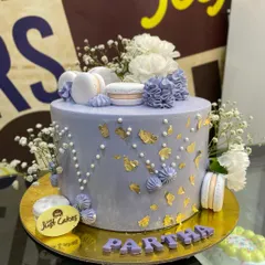 This elegant lavender cake is a beautiful example of a sophisticated design for a special occasion. It features delicate gold leaf accents, piped buttercream details, and is tastefully adorned with fresh baby's breath flowers and perfectly crafted macarons.