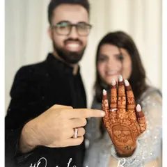 A fun and proud moment after the engagement. The couple joyfully shows off the bride's ring and intricate henna design.